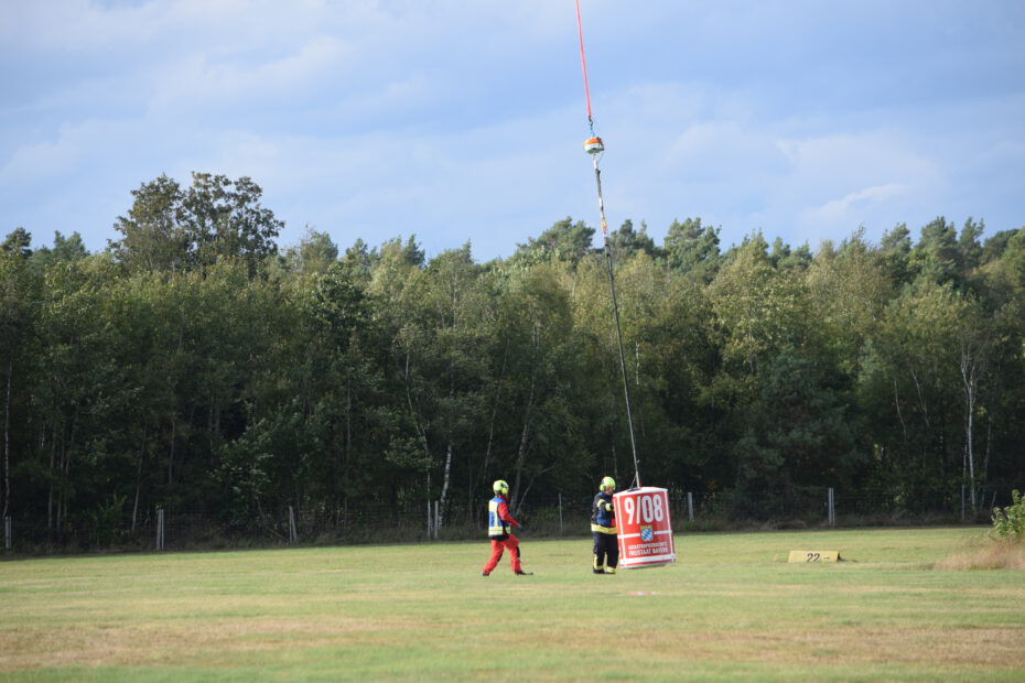 Firefighters mount the sensor platform between helicopter and water container